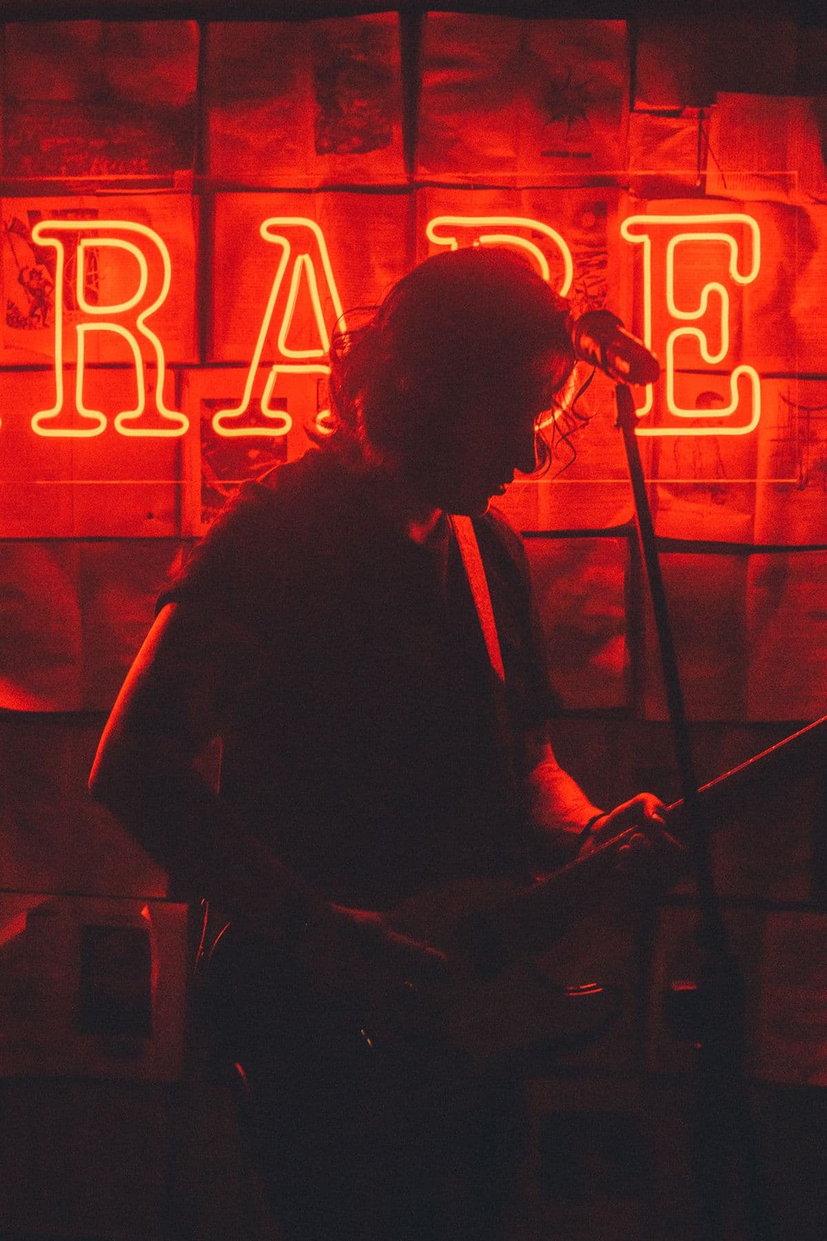 Silhouette d'un chanteur au micro devant une enseigne au néon rouge