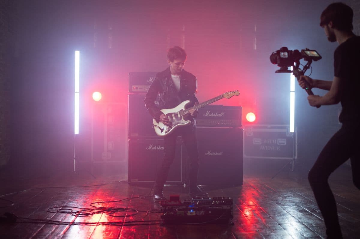 Guitariste sur une scène baignée de lumière rose et rouge